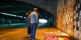 Betroffene stehen im Tunnel in der Nähe des Unglücksortes vor Kerzen, die das Datum 24.07.2010 zeigen.