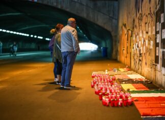 Betroffene stehen im Tunnel in der Nähe des Unglücksortes vor Kerzen, die das Datum 24.07.2010 zeigen.