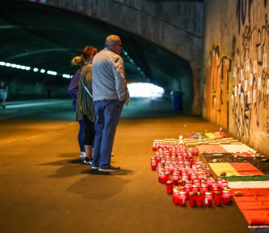 Betroffene stehen im Tunnel in der Nähe des Unglücksortes vor Kerzen, die das Datum 24.07.2010 zeigen.