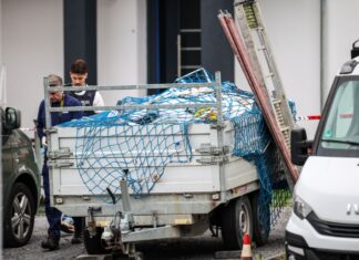 Polizeibeamte gehen neben Handwerkerfahrzeugen entlang. Hier war am vergangenen Freitag ein Handwerker erschossen worden. (Archivbild)