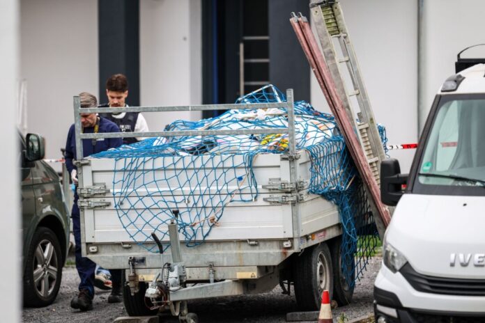 Polizeibeamte gehen neben Handwerkerfahrzeugen entlang. Hier war am vergangenen Freitag ein Handwerker erschossen worden. (Archivbild)