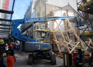 Einsatzkräfte stützen eine einsturzgefährdete Gebäudewand an einer Baustelle.