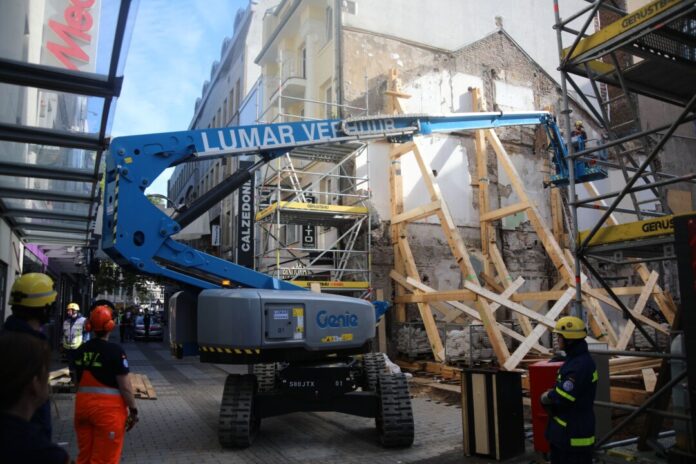 Einsatzkräfte stützen eine einsturzgefährdete Gebäudewand an einer Baustelle.