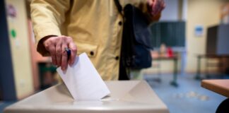 Eine Frau wirft einen Wahlschein in eine Wahlurne (Symbolbild)