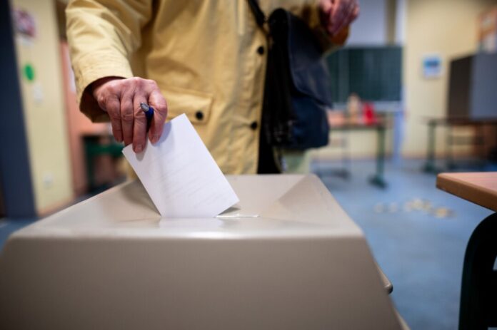 Eine Frau wirft einen Wahlschein in eine Wahlurne (Symbolbild)