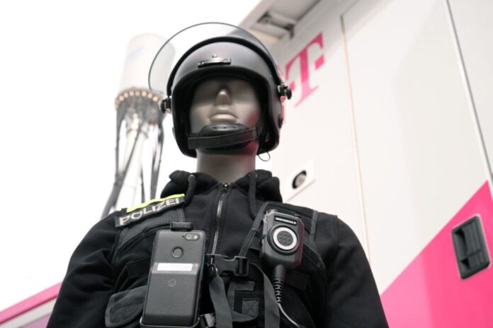 Eine Puppe in Polizei-Uniform zeigt, wie es gehen soll: An ihrer Uniform ist nicht nur ein Funkgerät, sondern auch ein Smartphone befestigt. Die Einsatzzentrale kann sich auf das Smartphone schalten und dank der Kamera sehen, was gerade los ist.