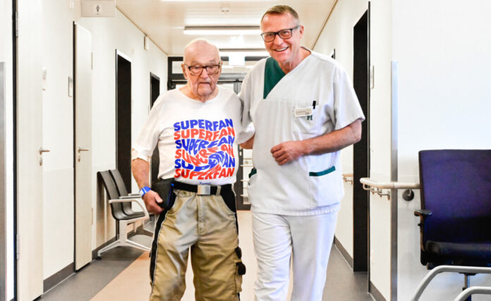 Chefarzt Dr. med. Peter Riess freut sich über die erstaunliche Mobilität seines Patienten. Der Wittgensteiner Egon Lange ließ sich vor wenigen Tagen im Helios-Klinikum Niederberg in Velbert sein zweites Kniegelenk ersetzen – um weiter Marathon wandern und täglich Sport treiben zu können. Foto: Helios/Michael Mutzberg