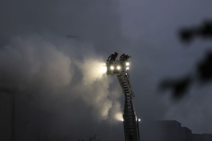 Sperrmüll brennt in großer Halle - Feuer nicht unter Kontrolle Über eine Drehleiter kämpfen Feuerwehrleute an der Sperrmüll-Halle gegen den Brand.
