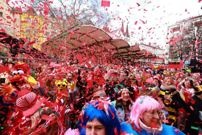 Weiberfastnacht im Rheinland - Beginn des Straßenkarnevals Perücken auf dem Kopf, Konfetti in der Luft: Karnevalisten beim Feiern. (Archivbild)