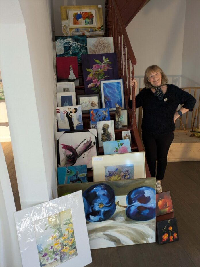 Elfi Lütcke, Vorsitzende des Kunstvereins Ratingen, in den neuen Ausstellungsräumen neben den Preisen für das Gewinnspiel, Bild: Künstler Verein