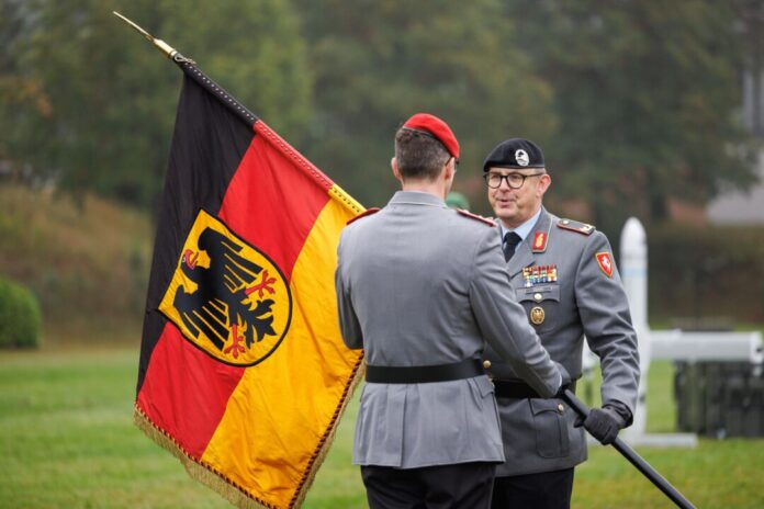 Brigadegeneral Marco Eggert (r) übergibt eine Deutsche Fahne beim Feierlichen Appell für das neu aufgestellte Artilleriebataillon 215 in der General-Feldmarschall-Rommel-Kaserne.