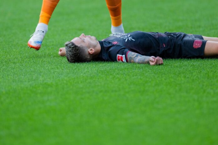 Bayer Leverkusens Kapitän Alejandro Grimaldo liegt nach einem Zusammenprall mit dem eigenen Mann benommen auf dem Boden. 