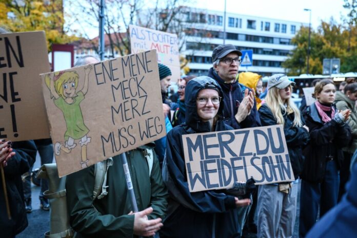 Rund 2.400 Menschen demonstrieren in NRW: «Merz muss weg» Ein Demonstrant hält ein Schild mit der Aufschrift «Merz, du Weidelsohn» hoch während einer Protestaktion nach den Aussagen von Bundeskanzler Merz zu Stadtbild und Migration.