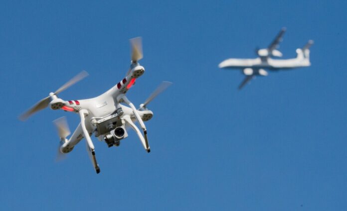 Eine private Drohne fliegt in weiter Entfernung von einem Flugzeug, das im Anflug auf den Flughafen Düsseldorf ist. (Symbolbild)