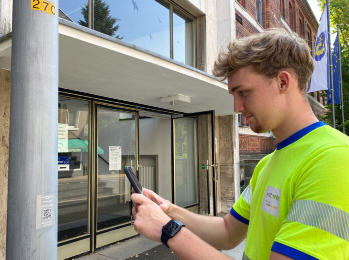 Westnetz-Mitarbeiter Tim van Terwingen testet den QR-Code an einer Leuchte vor dem Rathaus. Foto: Westenergie AG / Judith Meuter