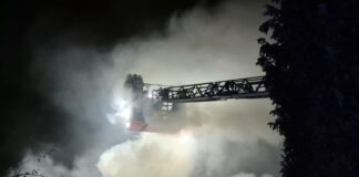 Einsatzkräfte der Feuerwehr löschen von einer Drehleiter den Brand in einem Wohnhaus.