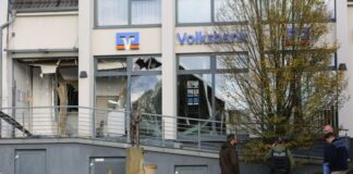 Ermittler der Polizei stehen in Paderborn vor einer beschädigten Bankfiliale. 