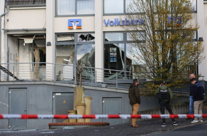 Ermittler der Polizei stehen in Paderborn vor einer beschädigten Bankfiliale. 