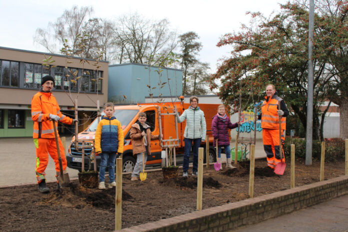 Apfelbäume für die GGS Unterfeldhaus Initiator und Bauhof-Mitarbeiter Marten Wirtz (1.v.r.) pflanzt gemeinsam mit einem Kollegen sowie Standortleiterin Mechthild Histerkamp (3.v.r.) und den Schulkindern Marie (2.v.r.), Kian (5.v.r.) und Fin (4.v.r.). Foto: Stadt Erkrath
