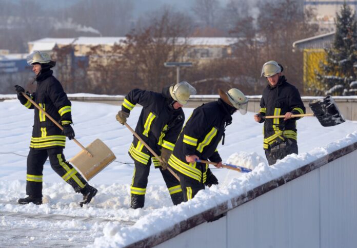 Schnee auf der Turnhalle Ein Foto aus dem Jahr 2010 aus Gera in Thüringen: Feuerwehrleute beseitigen Schnee vom Dach einer Turnhalle. So eine Unterstützung hätten die Menschen in Goch (NRW) nun wohl auch gern. (Archivbild)