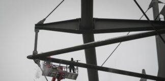 Arbeiter mit einem Hubsteiger entfernen Eis und Schnee von den Trägern des Stadiondachs in Hamburg.