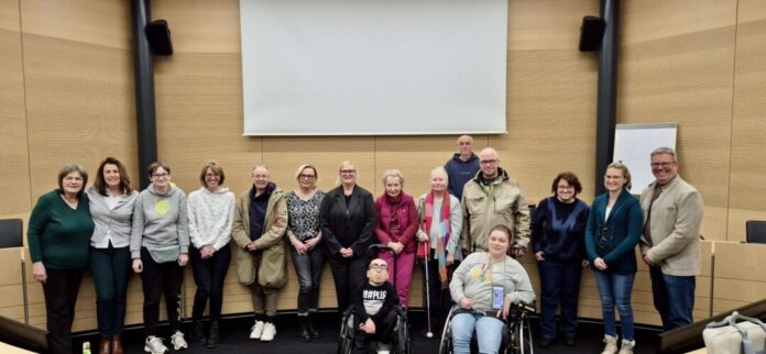 Beirat MmB Der neu konstituierte Beirat für Menschen mit Behinderungen bei seiner Sitzung am 5. Februar 2026. In der vorderen Reihe sitzen zwei Mitglieder des Beirats im Rollstuhl Can Kutan, Daniela Buchwald; dahinter Beiratsmitglieder in einer langen Reihe Karin Keune, Karen Tindall, Lisa Großhanten, Nicola Poßberg, Claudia Zenker, Elke Gigante, Kirsten Gerding, Annette van Deenen, Petra Clemens-Keoke, Marc Kronenberger, Andrea Behrens, Madita Stiefken, Sozialdezerent Harald Filip,. Im Hintergrund steht der technische Inklusionsbeauftragte Christoph Eschenbach., Bild: Privat