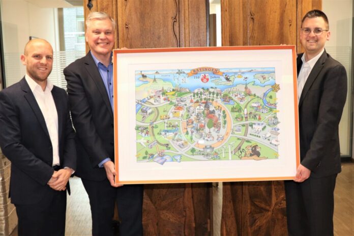 2026-04-13-Wimmelbild DKV Bürgermeister Patrick Anders (rechts) freut sich sehr über das gelungene Wimmelbild zum Stadtjubiläum, das Jesper Erichsen, Mitglied der Geschäftsführung, und Philipp Anger von DKV Mobility im Rathaus überreichten. Foto: Stadt Ratingen