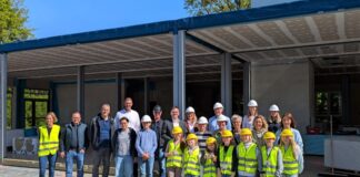 Schülerinnen und Schüler, Lehrkräfte und Eltern der Heinrich-Schmitz-Schule sowie Bürgermeister Patrick Anders und Beigeordneter Martin Gentzsch ließen sich von den Baufachleuten der Verwaltung und der Firma Kleusberg den Baufortschritt an der neuen Schule erläutern. Foto: Stadt Ratingen