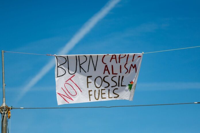 Aufbau vor Klimacamp gegen den Ausbau von Gaskraftwerken Ein Banner mit der Aufschrift «Burn Capitalism not Fossil Fuels» ist an einem Seil im Klimacamp befestigt. (Archivbild)