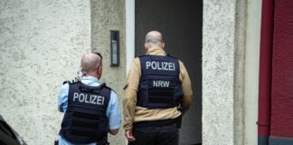 Offene Geldstrafe: Verurteilter «Reichsbürger» festgenommen Polizisten stehen vor einem Hauseingang. Ein mutmaßlich der «Reichsbürger»-Szene angehörender Mann ist in Wuppertal von der Polizei festgenommen worden. (Symbolbild)