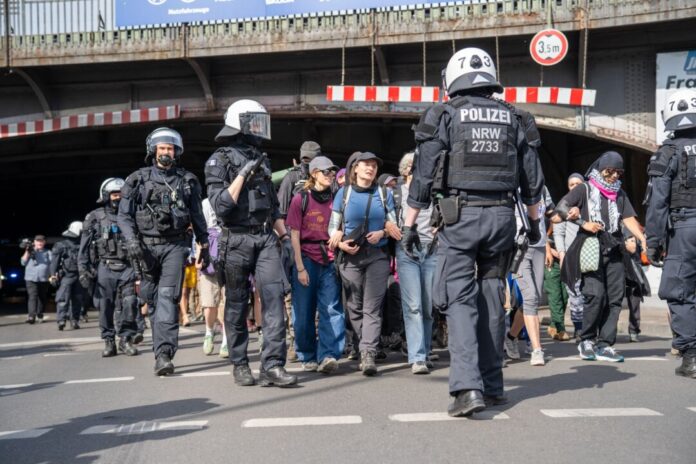 Fortsetzung Klimacamp gegen Ausbau von Gaskraftwerken Polizisten schirmen Demonstranten bei einer Versammlung ab.