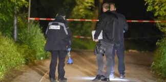 Schwerverletzter nach Streit – Fahndung mit Hubschrauber Einsatzkräfte stehen auf einer Straße an einem Tatort und sichern Spuren.