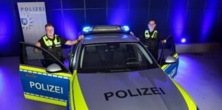 Nach Hamburger Vorstoß: Kein Dauer-Blaulicht bei NRW-Polizei Eine Beamtin und ein Beamter der Polizei Hamburg stehen vor einem Streifenwagen mit dem neuen «Präsenzlicht»