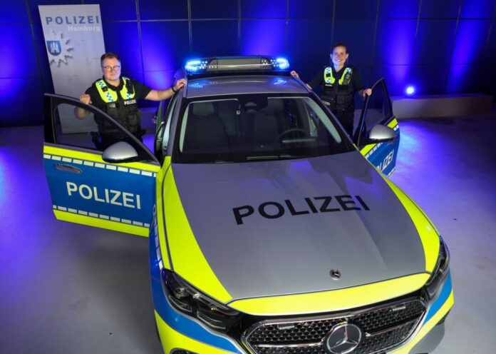 LED-Licht für Hamburgs Funkstreifenwagen Eine Beamtin und ein Beamter der Polizei Hamburg stehen vor einem Streifenwagen mit dem neuen «Präsenzlicht»