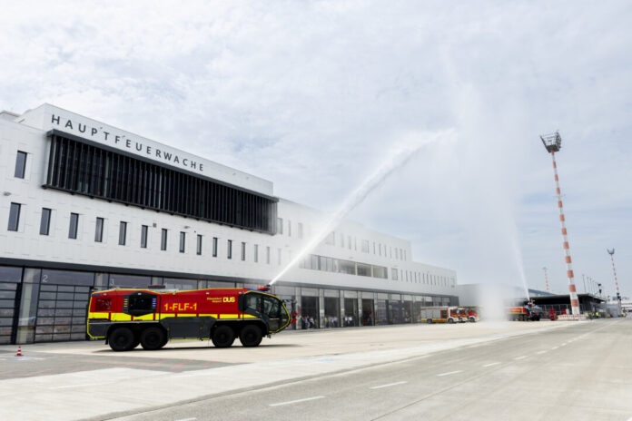 Standesgemäße Einweihung für eine der modernsten Feuerwachen Europas: „Wasser marsch!“ hieß es bei der Eröffnungsfeier. Mit Wasserfontänen aus zwei Panther-Löschfahrzeugen feierten die Feuerwehrleute des Airports ihr neues Einsatzgebäude. Rund 100 Gäste nahmen an der offiziellen Einweihung teil. Foto: Flughafen Düsseldorf / Andreas Wiese Standesgemäße Einweihung für eine der modernsten Feuerwachen Europas: „Wasser marsch!“ hieß es bei der Eröffnungsfeier. Mit Wasserfontänen aus zwei Panther-Löschfahrzeugen feierten die Feuerwehrleute des Airports ihr neues Einsatzgebäude. Rund 100 Gäste nahmen an der offiziellen Einweihung teil. Foto: Flughafen Düsseldorf / Andreas Wiese