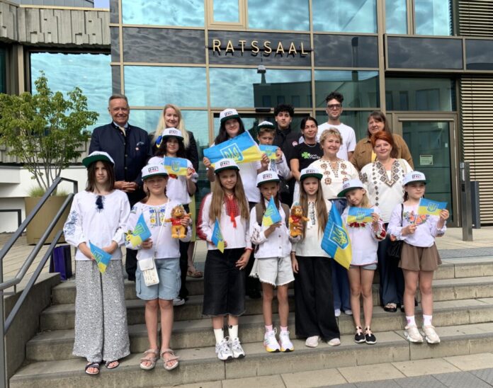 2026-07-07-Empfang ukrainische Schülergruppe Mit neuen Ratingen-Käppis ausgestattet, versammelte sich die ukrainische Schülergruppe mit ihren Lehrerinnen sowie den Betreuern vor Ort nach dem Empfang durch den stellvertretenden Bürgermeister Michael Droste (hintere Reihe links) vor dem Eingang zum Ratssaal. Foto: Stadt Ratingen