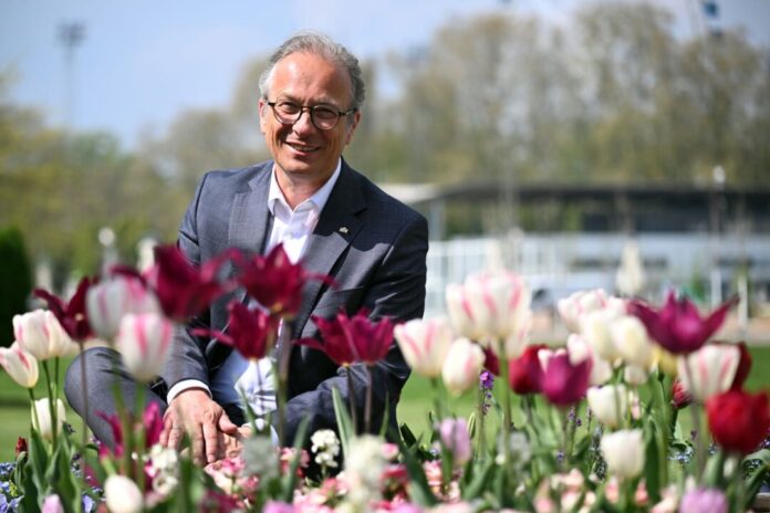 Landesgartenschau Neuss Bürgermeister Reiner Breuer (SPD) sitzt auf dem Gelände der Landesgartenschau zwischen den Blumen.