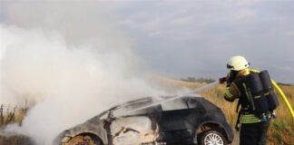 Autofahrerin rettet 82-Jährigen aus brennendem Wagen Eine Einsatzkraft der Feuerwehr löscht ein brennendes Auto, aus dem zuvor ein 82-Jähriger gerettet wurde.