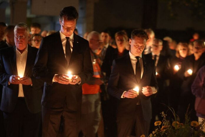 Gedenken an islamistischen Terroranschlag in Solingen Ministerpräsident Hendrik Wüst und Oberbürgermeister Daniel halten Kerzen in der Hand.