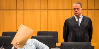 Hetzjagd mit sieben Autos: Angeklagter bestreitet Vorwürfe Der Angeklagte hält sich vor Beginn des Prozesses im Saal des Landgerichts einen Umschlag vor das Gesicht.