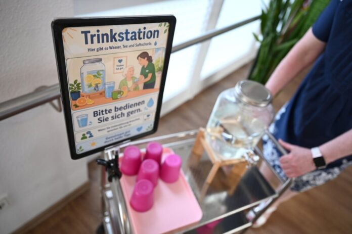 Hitzeschutz für pflegebedürftige Menschen Eine Frau schiebt in einem Pflegeheim einen Wagen mit Trinkbechern und Wasser. (Symbolbild)