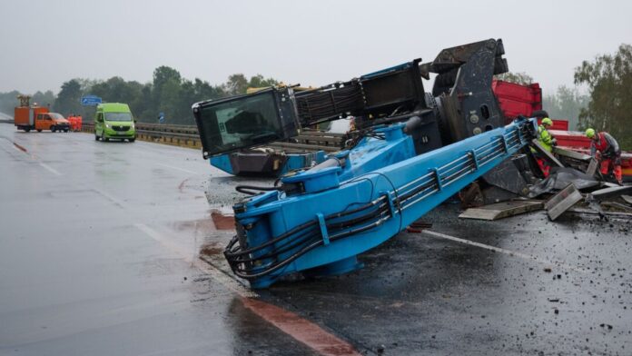Schwertransporter mit Baukran umgekippt Der Schwertransporter hatte einen großen Kran geladen, der bei dem Unfall über die Mittelschutzplanke kippte.