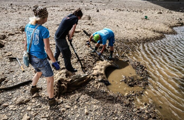 Müllsammler am Rhein Freiwillige versuchen bei einer Müllsammelaktion bei Niedrigwasser am Rhein einen großen Reifen auszugraben. (Archivbild)
