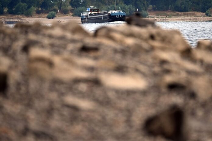 Niedrigwasser im Rhein Schiffe fahren an Steinen vorbei, die normalerweise unter der Wasseroberfläche liegen.