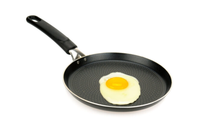 Fried eggs in pan isolated on white background. Die Verbraucherzentrale NRW gibt Tipps zum Kauf von Bratpfannen ohne „Ewigkeitschemikalien“. Foto: VZ NRW/adpic