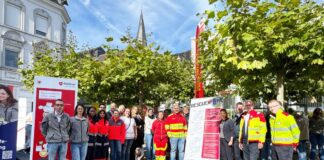 Kreis Mettmann: Jeder kann bei Herz-Kreislauf-Stillstand helfen Der ärztliche Leiter des Rettungsdienstes im Kreis Mettmann, Dr. Arne Köster, erklärt Landrätin Dr. Bettina Warnecke die richtigen Schritte bei einer Herzdruckmassage. Foto: Kreis Mettmann 2. Vertreterinnen und Vertreter der teilnehmenden Institutionen und Organisationen beim Tag der Wiederbelebung 2026 auf dem Jubiläumsplatz in Mettmann. Foto: Kreis Mettmann