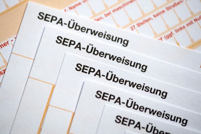 SEPA-Überweisungsscheine liegen auf einem Tisch Ein Ex-Sparkassen-Mitarbeiter soll sich Geld von fremden Konten auf eigene Konten überwiesen haben. (Archivbild)