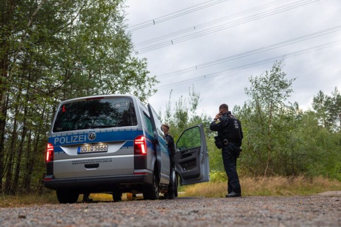 Polizeieinsatz in Sachsen Polizeikräfte stehen in einem Waldstück unter einer Stromtrasse nahe dem Ort Schleife im Landkreis Görlitz.