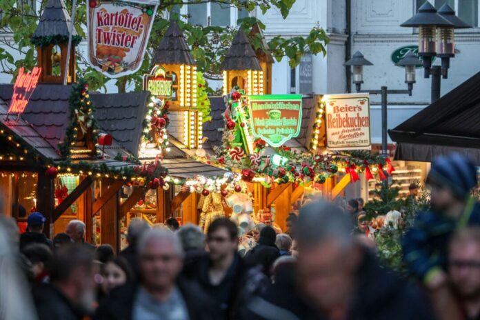 Eröffnung des Weihnachtsmarkts im Essener Stadtteil Steele Besucher gehen an beleuchteten Verkaufshütten vorbei.