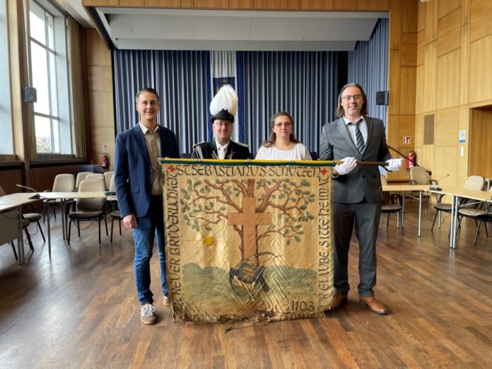 Schützenfahne 2 Im Ratssaal übergaben Svenja Kircher und 1. Brudermeister Daniel Gebauer die historische Schützenfahren der St. Sebastinaus Schützenbruderschaft als Dauerleihgabe für die Stadt an Bürgermeister André Bär und Stadtarchivar Marinko Betker. Foto: Kreisstadt Mettmann